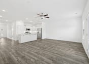 Thumbnail 7 of 27 - A spacious room with a ceiling fan and wooden flooring.
