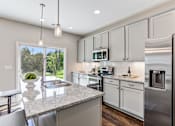 Thumbnail 3 of 19 - A modern kitchen with granite countertops and stainless steel appliances.