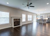 Thumbnail 13 of 19 - A spacious living room with a fireplace and a kitchen in the background.