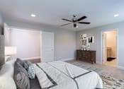 Thumbnail 8 of 19 - A bedroom with a bed, dresser, and ceiling fan.