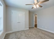 Thumbnail 18 of 19 - A room with a ceiling fan and carpeted floor.