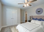 Thumbnail 11 of 19 - A bedroom with a white bed and a ceiling fan.