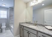 Thumbnail 19 of 19 - A bathroom with a granite countertop and a white toilet.