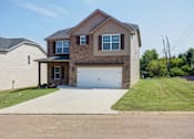 Thumbnail 1 of 19 - A two-story house with a garage is surrounded by a grassy area and a sidewalk.