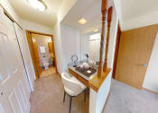 Thumbnail 18 of 21 - a bedroom with a desk and a bathroom with a toilet and a sink