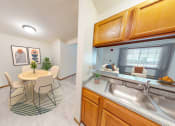 Thumbnail 34 of 35 - a dining room with a table and chairs and a kitchen with a sink