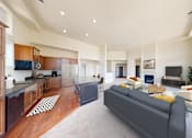 Thumbnail 2 of 15 - a living room with a couch and a kitchen with a table
