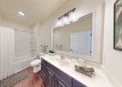 Thumbnail 35 of 38 - A bathroom with a toilet, sink, and mirror.