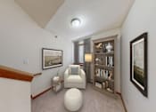 Thumbnail 5 of 26 - A living room with a white chair and a bookshelf.