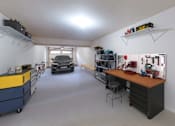 Thumbnail 30 of 30 - A garage with a workbench and a car in the background.