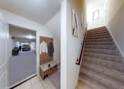 Thumbnail 29 of 30 - A hallway with a staircase and a bench.