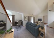 Thumbnail 3 of 42 - A living room with a grey couch and a wooden table.