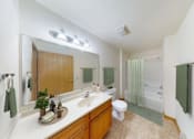 Thumbnail 7 of 12 - A bathroom with a sink, mirror, toilet, and shower.