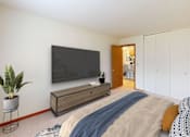 Thumbnail 6 of 27 - A bedroom with a bed, a TV, and a plant.