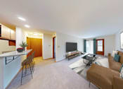 Thumbnail 2 of 27 - A living room with a brown couch and a television.