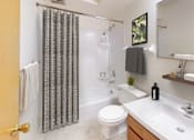 Thumbnail 7 of 27 - A bathroom with a toilet, sink, and shower curtain.