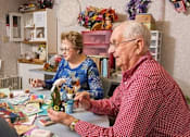 Thumbnail 5 of 12 - an older man and woman sitting at a table playing with toys