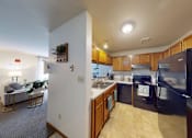 Thumbnail 4 of 50 - A kitchen with a black refrigerator and wooden cabinets.