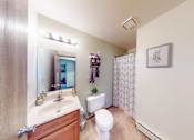 Thumbnail 5 of 50 - A bathroom with a toilet, sink, and mirror.