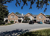 Thumbnail 18 of 28 - a large brick house with cars parked in front of it