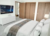 Thumbnail 6 of 28 - a bedroom with a bed and a tv on the wall