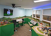 Thumbnail 47 of 49 - A room with a table, chairs, and a model train set.