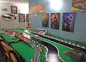 Thumbnail 44 of 49 - A table with a green tablecloth has a toy race track on it.