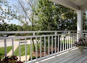 Thumbnail 8 of 14 - A white porch with a flower pot on it.
