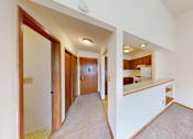 Thumbnail 7 of 10 - A hallway with a carpeted floor and white walls.