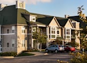 Thumbnail 9 of 21 - a large apartment building with cars parked in front of it