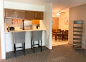 Thumbnail 26 of 50 - a kitchen with a bar and a dining room with a table and chairs