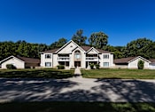 Thumbnail 46 of 50 - a large white house with a driveway and lawn