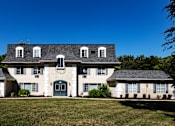 Thumbnail 50 of 50 - a large white house with a gray roof and a lawn
