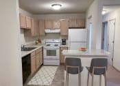 Thumbnail 17 of 22 - a kitchen with white appliances and a counter with two chairs