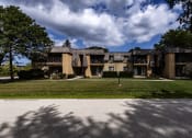 Thumbnail 15 of 21 - an apartment building with a lawn and a cloudy sky