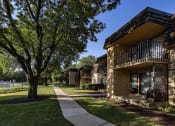 Thumbnail 10 of 21 - apartments with a sidewalk and trees in front of a building