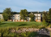 Thumbnail 23 of 28 - a grassy area with a pond in front of an apartment complex