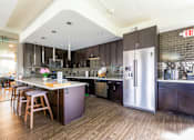 Thumbnail 71 of 124 - A kitchen with a refrigerator, stove, and bar stools.