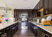 Thumbnail 66 of 124 - A kitchen with black cabinets and a stainless steel oven.