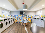 Thumbnail 79 of 124 - A laundromat with a row of washing machines and a row of dryers.