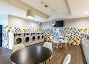 Thumbnail 89 of 124 - A laundry room with a washer and dryer on the wall and a table in the middle.