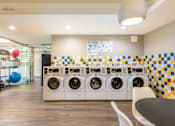 Thumbnail 92 of 124 - A laundromat with a row of washers and dryers.