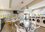 Thumbnail 91 of 124 - A laundromat with washers and dryers and a table and chairs.