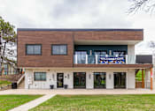 Thumbnail 115 of 124 - A modern building with a brown and white facade and a banner that says "Welcome Home".