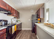 Thumbnail 69 of 124 - A kitchen with dark wood cabinets and a black refrigerator.