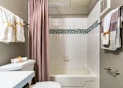 Thumbnail 48 of 124 - A bathroom with a white tub, a pink shower curtain, and a white towel hanging on the towel rack.