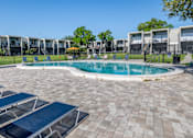 Thumbnail 34 of 53 - A round swimming pool surrounded by a brick patio and lounge chairs.