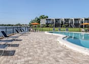 Thumbnail 37 of 53 - A pool area with sun loungers and a clear blue sky.
