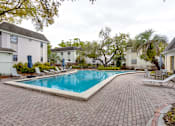 Thumbnail 47 of 47 - A swimming pool surrounded by a brick patio and lounge chairs.