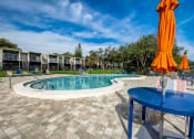 Thumbnail 28 of 47 - a resort style pool with orange umbrellas and a blue table